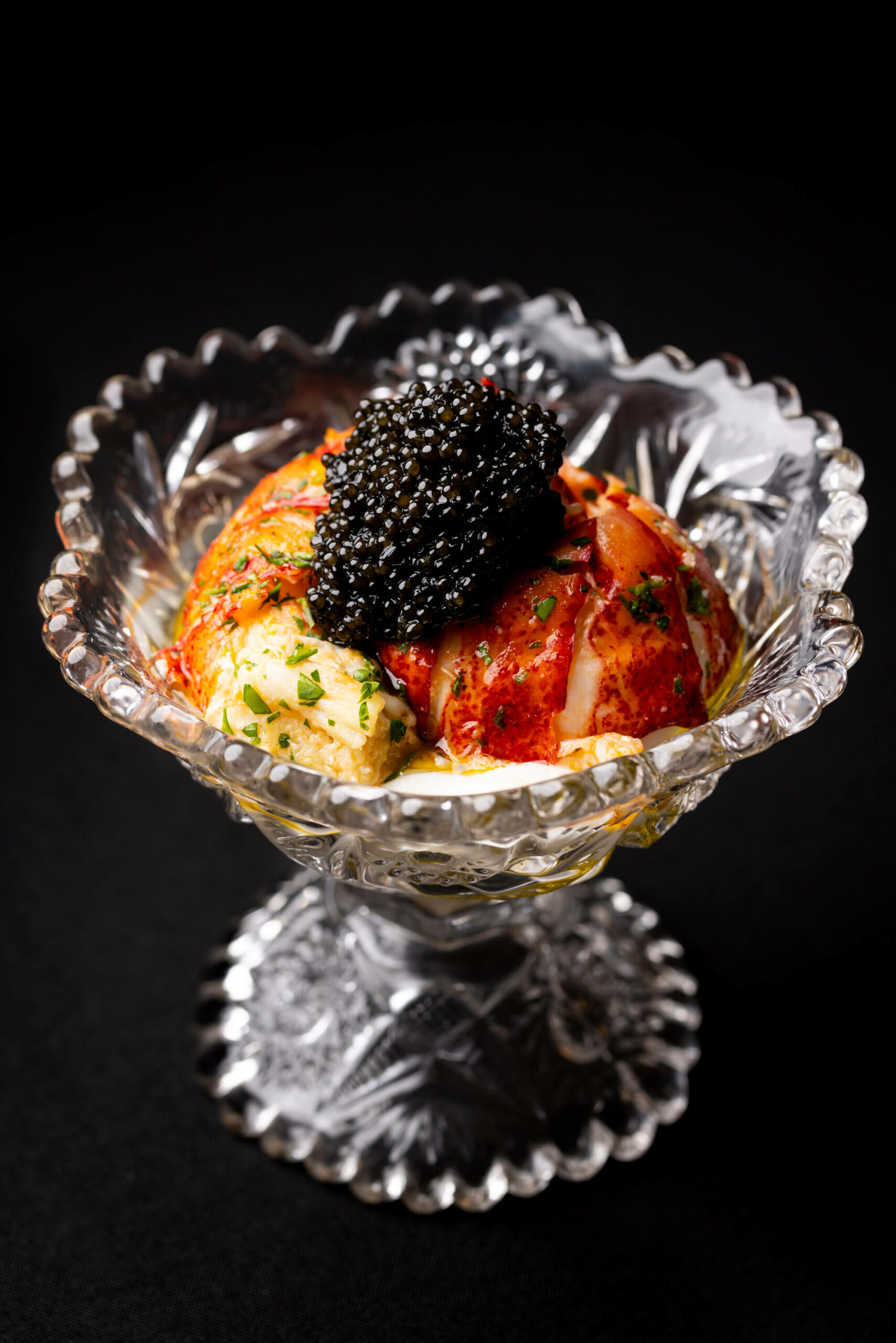 A luxurious presentation featuring caviar and lobster served in an elegant crystal bowl, highlighting a fusion of flavors.