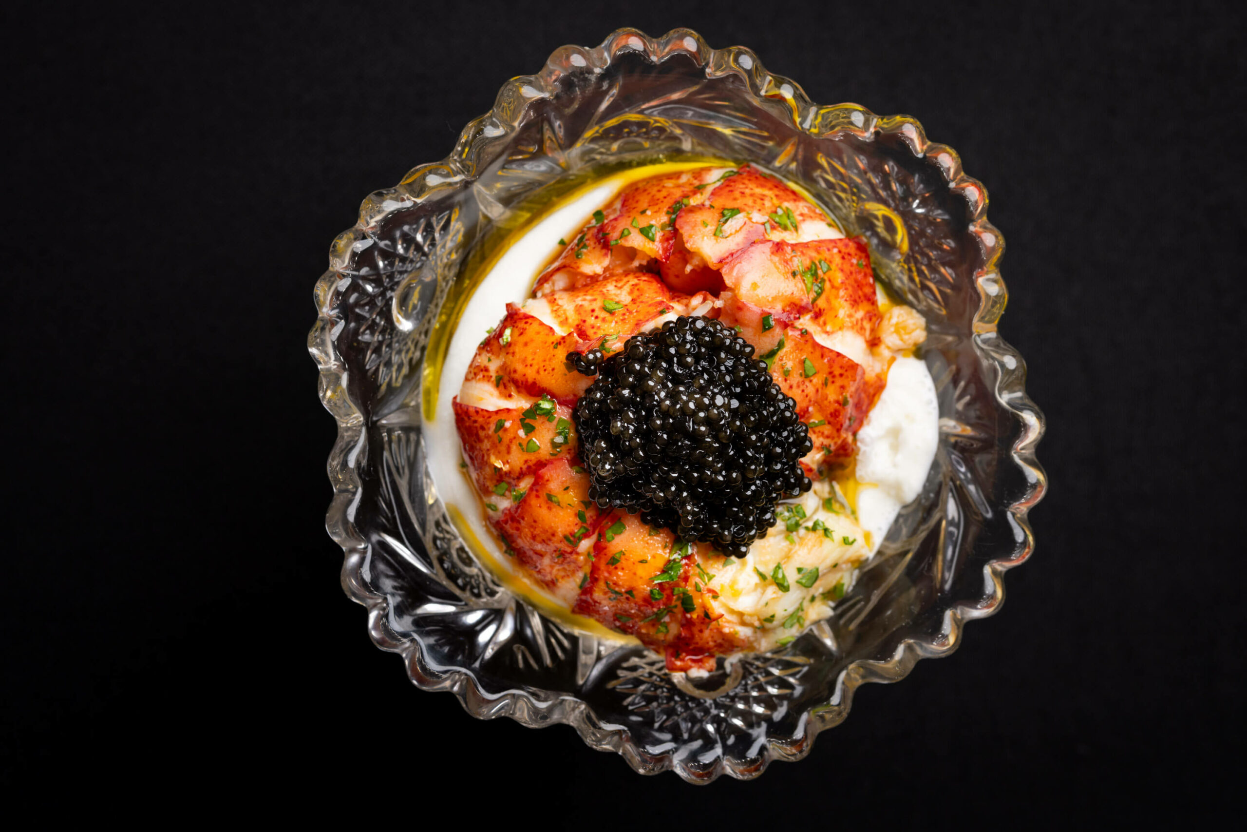 A top-down perspective showcasing the detailed arrangement of caviar and lobster in a decorative glass.