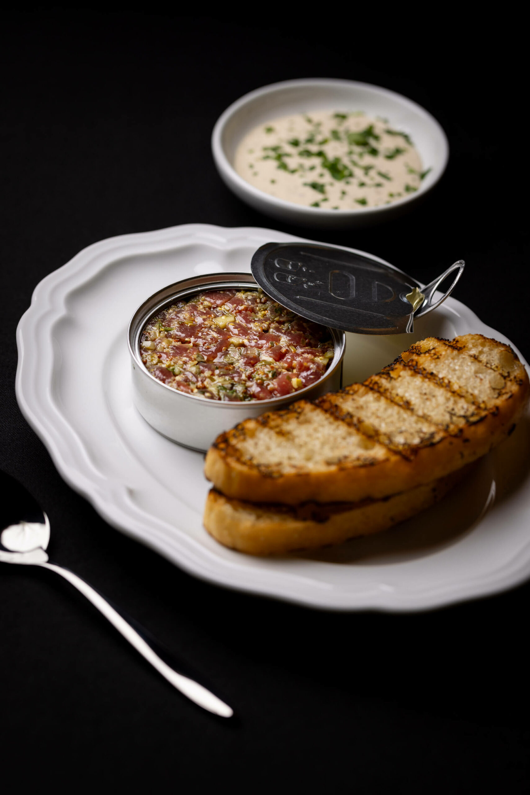 A vertical shot highlighting the setup of tuna tartare, grilled bread, and the herb dip for an elegant presentation.