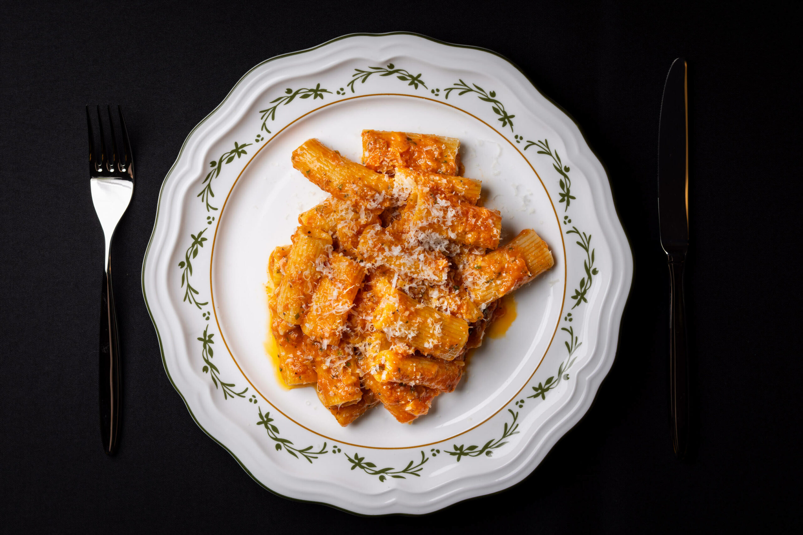 An overhead view of the classic pasta dish served with a fork and knife, emphasizing its presentation.