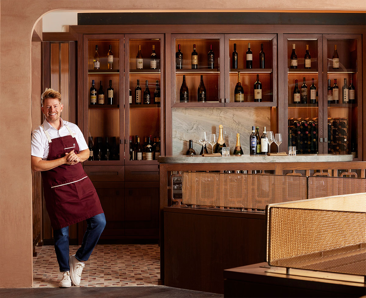 Chef Richard Blais leaning casually against the wine bar inside La Zozzona.