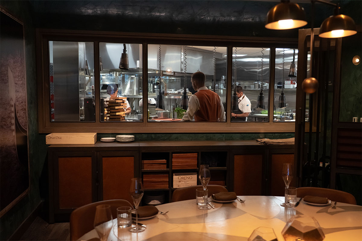 View from the chef’s table into the open kitchen, where the team prepares dishes behind a glass window.
