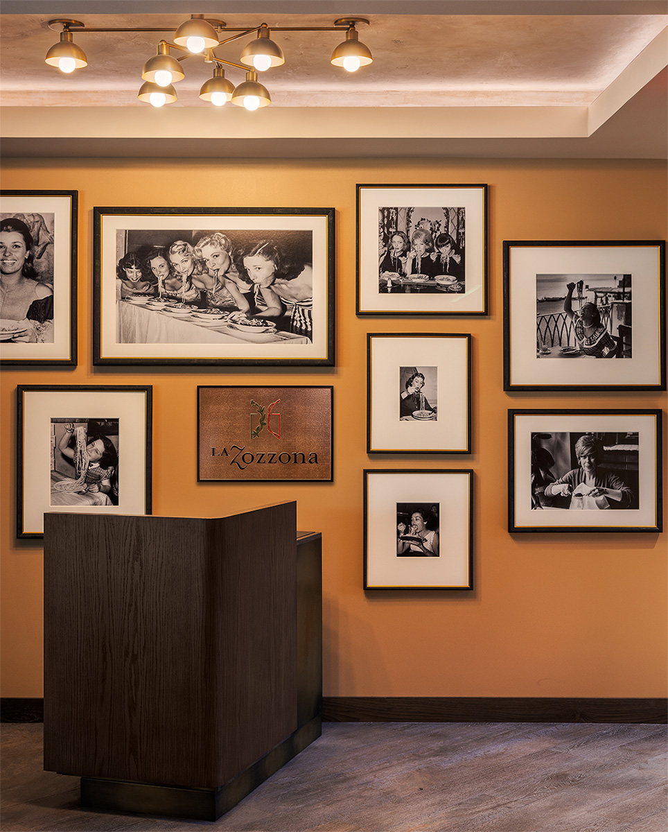 Reception area with framed black-and-white photos showcasing Italian dining culture and the La Zozzona logo.