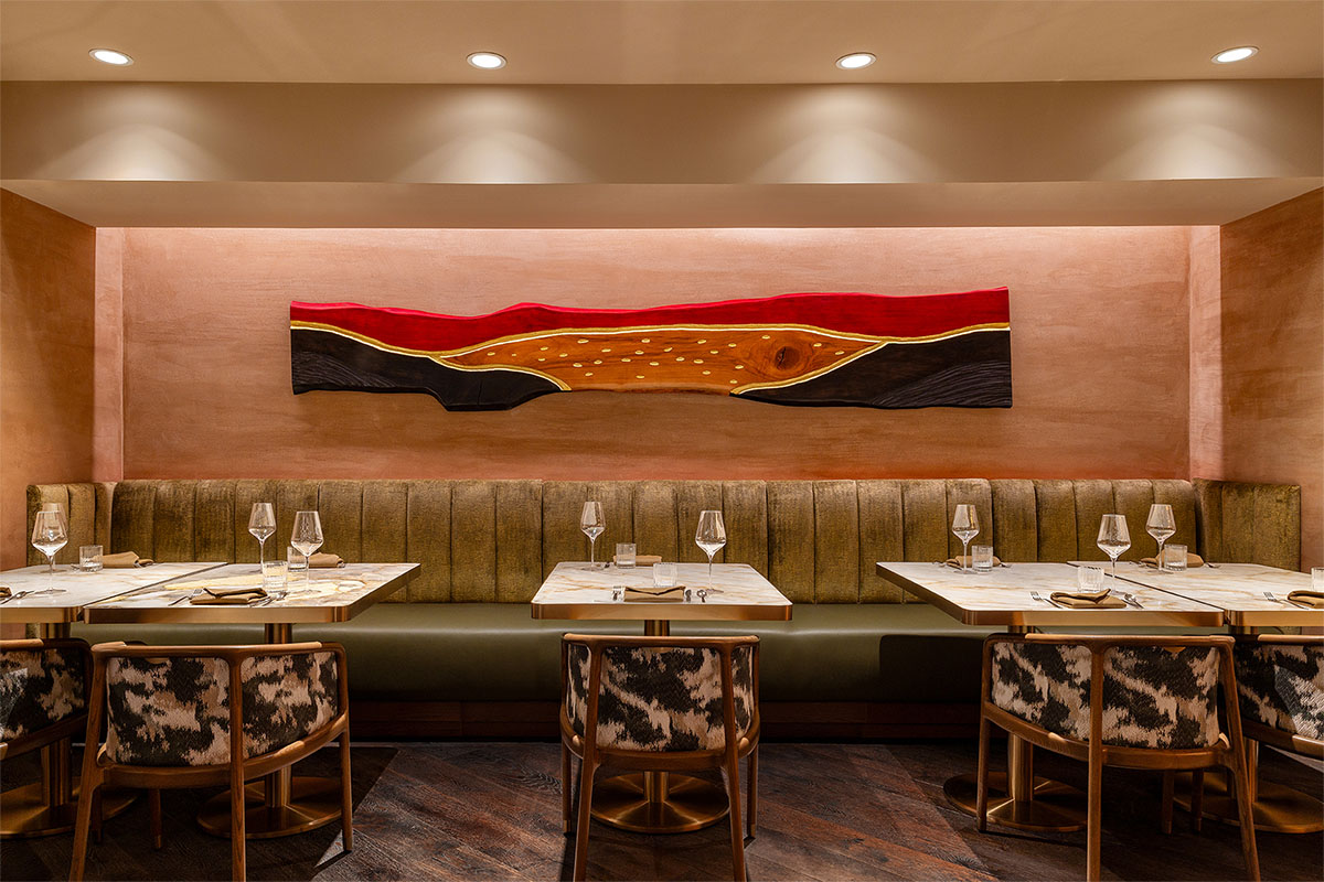 Cozy dining nook with olive-green bench seating and abstract wooden wall art.